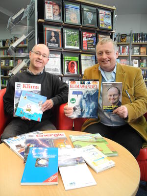 Bild vergr��ern: Ganz im Sinne des Klimaschutzes: Thomas Vitt (li.) und Martin Rabe (re.) pr�sentieren ausgew�hlte Medien zum Klimawandel, den Burbach lokal gestaltet. Insgesamt sind rund 20.000 &euro; f�r Neuanschaffungen 2012 investiert worden.