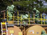 Bild vergr��ern: Einsatzkr�fte im Chemikalien-Schutzanzug (CSA) dichten die Leckage des Tanks ab.