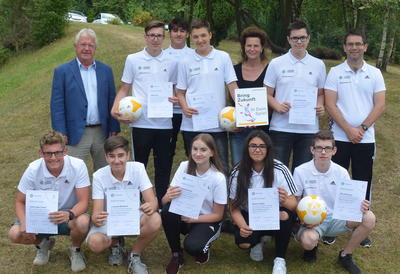Bild vergr��ern: Schulleiterin Frau Ermert-Heinz, Herr Antczak, Mitglied der Kommission Sportverein / Schule / Kita vom FLVW und DFB-Junior-Coach Ausbilder Herr B�chle freuen sich gemeinsam mit unseren DFB-Junior-Coaches �ber die erfolgreiche Ausbildung. Der Pate der Commerzbank, Herr Ebach, war leider verhindert.