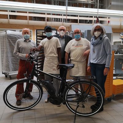 Bild vergr��ern: Peter Ginsberg (Fl�chtlingshilfe), Alliou Keba Diallo (Auszubildender), Hubert Multhaup (Fl�chtlingshilfe), Michael Prescher (Backstubenleiter) und Andrea Burrows (evangelische Kirche Burbach) freuen sich, dass der jungen Guineaner mit seinem E-Bike nun mobil ist und seinen Arbeitsplatz gut erreichen kann.