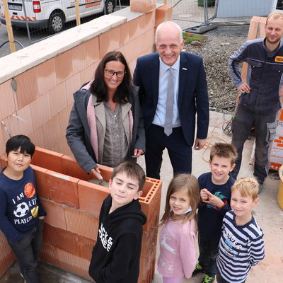 Bild vergr��ern: B�rgermeister Christoph Ewers und Schulleiterin Nicole Freitag betonierten im Beisein einiger OGS-Kinder die Zeitkapsel in das Mauerwerk.