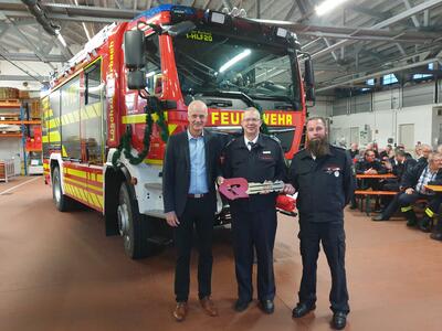 Bild vergr��ern: B�rgermeister Christoph Ewers �bergab den symbolischen Fahrzeugschl�ssel an den Leiter der Burbacher Feuerwehr, Gemeindebrandinspektor Markus Schwarze, und Einheitsf�hrer Tim Weber (v.l.).
