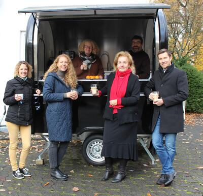 Bild vergr��ern: Verena Landau (vorne 2.v.l.) ist die neue Regionalmanagerin in der LEADER-Region 3-L�nder-Eck. Zum Einstand testet sie mit ihrer Kollegin Stefanie Schmidt, Roswitha Still, 1. Vorsitzende des Regionalvereins, Wilnsdorfs B�rgermeister Hannes Gieseler (vorne v.l.) den mobilen Caf�-Anh�nger der Ev.-Ref. Kirchengemeinde R�dgen-Wilnsdorf an, aus dem Pfarrer Chirstoph Otminghaus und Gemeindeschwester Sonja Sabel leckere Kaffeespezialit�ten reichten.