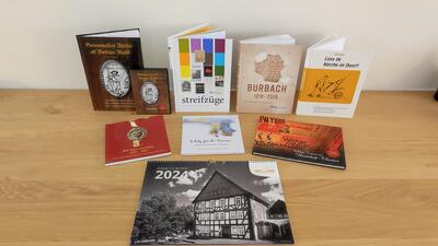Bild vergr��ern: Wandkalender 2024, Nachtw�chter-Bilderbuch und Festschrift sind nur einige der Burbacher Geschenkideen, die es aktuell in der Alten Vogtei gibt.