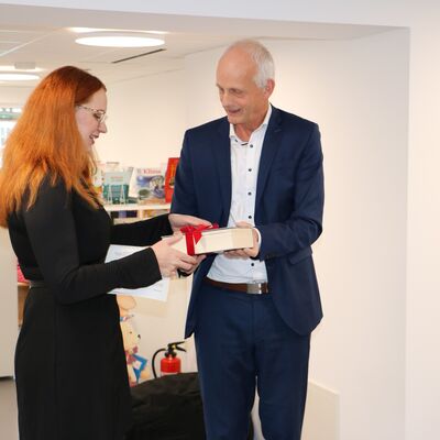 Bild vergr��ern: Versteckt in einer �dicken Schwarte� erhielt Magdalena Heide von B�rgermeister Christoph Ewers den symbolischen Schl�ssel zur B�cherei.