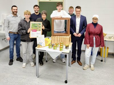Bild vergr��ern: Lehrer Matthias Sauer, Tim Jonas Schmidt, Jonas Leyener (Westenergie), Emil Schoeppner, Andreas Bauer, Ben Petri, B�rgermeister Jonas Becker und Esraa Al Refai (v.l.n.r.) freuen sich �ber den 1. Platz der Gemeinschaftlichen Sekundarschule beim Burbacher Westenergie Klimaschutzpreis 2025.