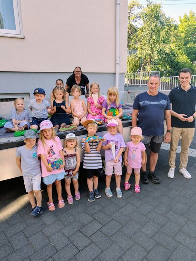 Bild vergr��ern: B�rgermeister Jonas Becker (r.) bedankte sich beim Bauhofleiter Frank Reinschmidt, den beiden Bauhofmitarbeiterinnen Christine Trapp und Anja Michalski (hinten v.l.n.r.) und einigen der jungen K�nstlerinnen und K�nstlern, die f�r die bunten Steine verantwortlich zeichnen.
