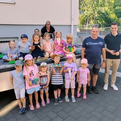 Bild vergr��ern: B�rgermeister Jonas Becker (r.) bedankte sich beim Bauhofleiter Frank Reinschmidt, den beiden Bauhofmitarbeiterinnen Christine Trapp und Anja Michalski (hinten v.l.n.r.) und einigen der jungen K�nstlerinnen und K�nstlern, die f�r die bunten Steine verantwortlich zeichnen.