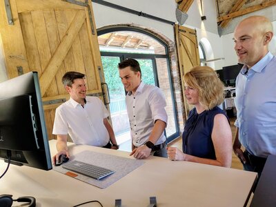 Bild vergr��ern: B�rgermeister Jonas Becker (2.v.l.) und Wirtschaftsf�rderer Christian Feigs (r.) lie�en sich von Dietrich und Tina Seibel in das T�tigkeitsfeld von fescon einf�hren.