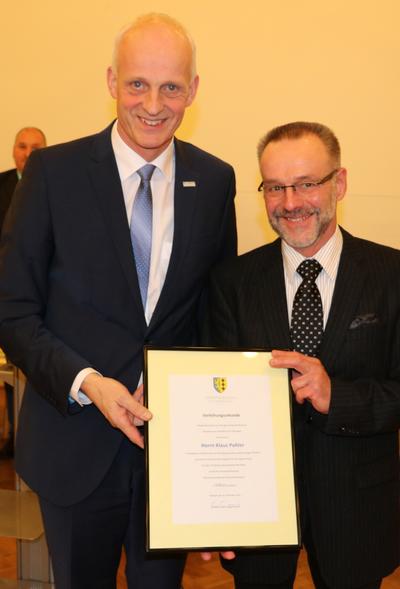 Bild vergr��ern: F�r die 10-j�hrige Mitgliedschaft im Rat der Gemeinde Burbach erhielt Klaus Pohler die Ehrenmedaille in Silber nebst Urkunde von B�rgermeister Christoph Ewers �berreicht.