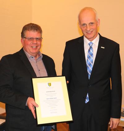 Bild vergr��ern: Achim Sahm (li.) wurde f�r seine langj�hrige kommunalpolitische Arbeit von B�rgermeister Christoph Ewers (re.) mit einer Urkunde und der Goldmedaille ausgezeichnet.